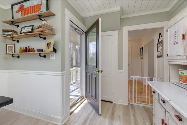 foyer featuring light wood-style flooring, wainscoting, wooden ceiling, and ornamental molding