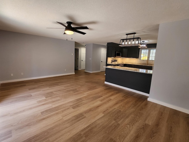 kitchen with appliances with stainless steel finishes, wood finished floors, light countertops, baseboards, and dark cabinetry