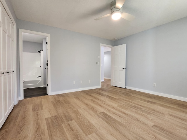 unfurnished bedroom featuring light wood-type flooring, baseboards, ceiling fan, and ensuite bath
