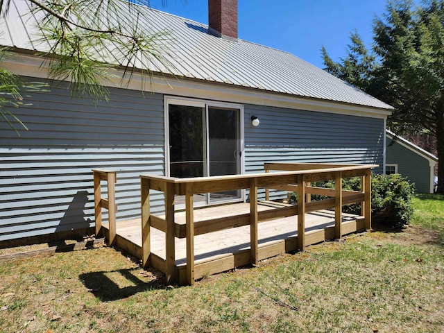 back of house featuring a yard, a chimney, metal roof, and a wooden deck