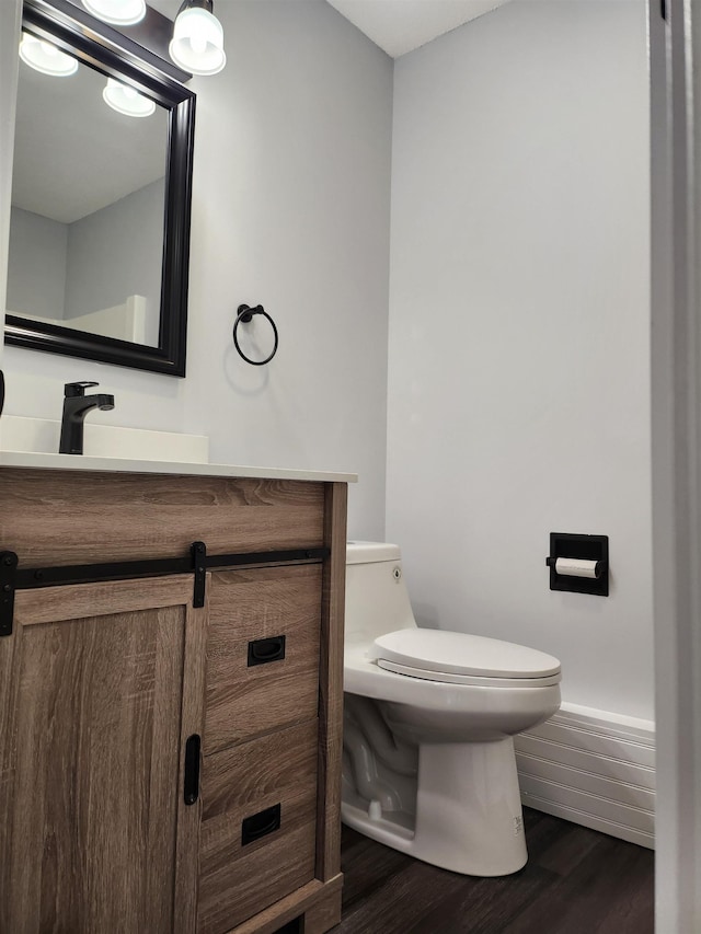 bathroom with vanity, baseboards, toilet, and wood finished floors