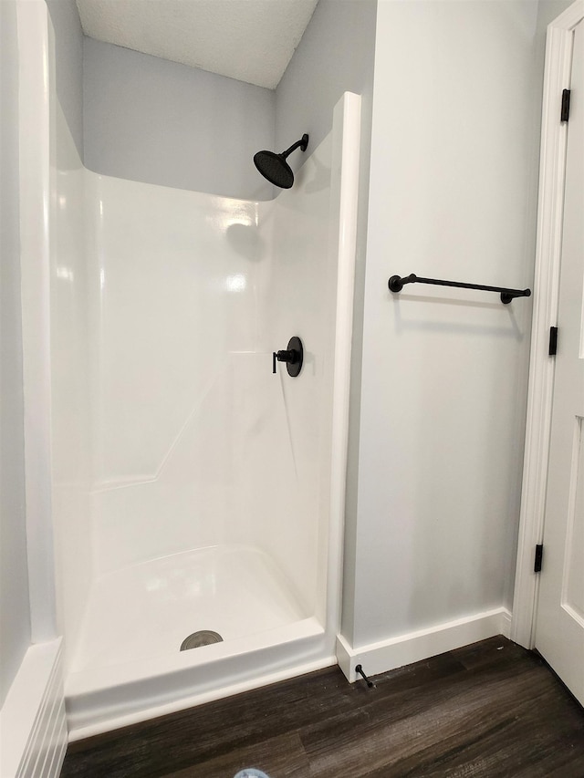 bathroom with a shower, baseboards, and wood finished floors