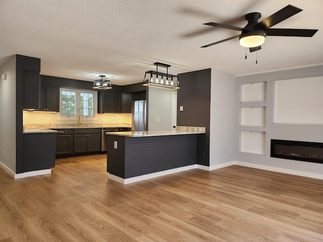 kitchen with tasteful backsplash, light countertops, a sink, a peninsula, and stainless steel appliances