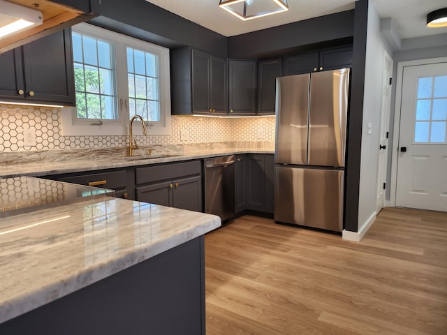 kitchen featuring stainless steel appliances, a healthy amount of sunlight, a sink, and light wood-type flooring