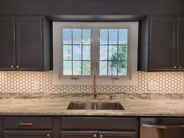 kitchen featuring stainless steel dishwasher, light stone counters, a sink, and tasteful backsplash