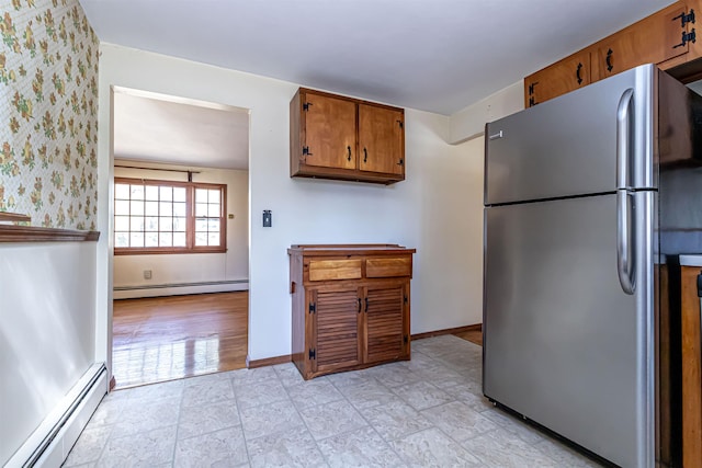 kitchen featuring freestanding refrigerator, brown cabinets, baseboards, and a baseboard radiator