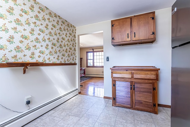 interior space with baseboards, wallpapered walls, baseboard heating, and freestanding refrigerator