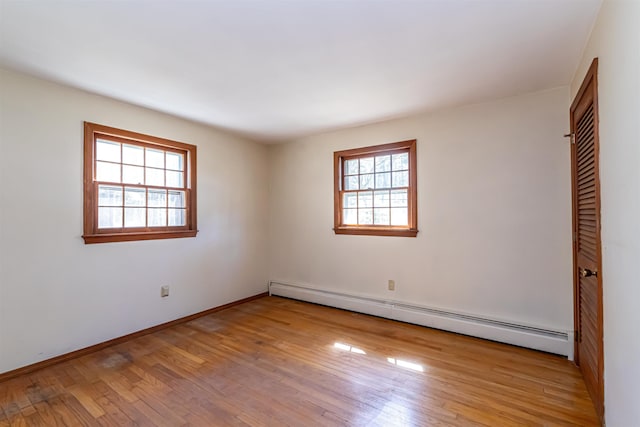 unfurnished room featuring baseboards, baseboard heating, and wood finished floors