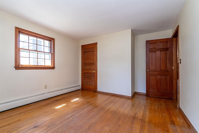 unfurnished room with baseboards, baseboard heating, and light wood-style flooring