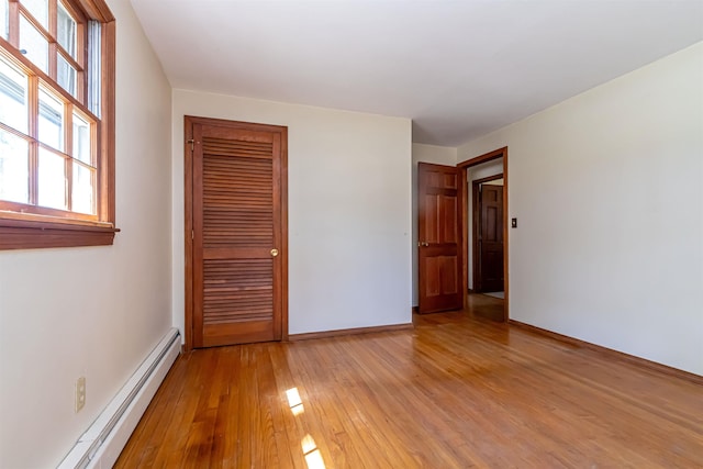 unfurnished room featuring baseboards, a baseboard heating unit, and light wood finished floors