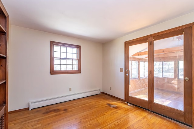 interior space featuring light wood finished floors, baseboard heating, and a wealth of natural light