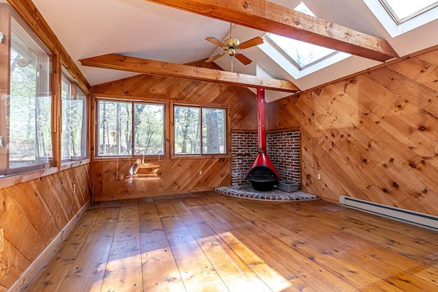 interior space with beamed ceiling, a skylight, a baseboard heating unit, and a wood stove