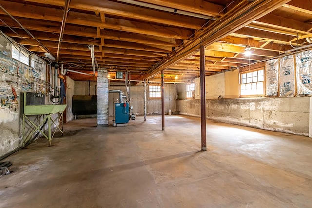 basement with a heating unit, heating fuel, and a wealth of natural light