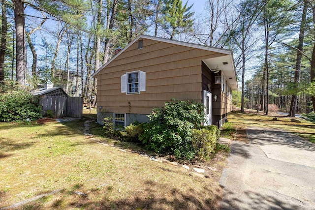 view of side of property featuring a lawn, fence, and driveway