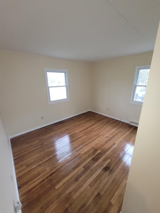 unfurnished room featuring baseboards, a wealth of natural light, and hardwood / wood-style flooring