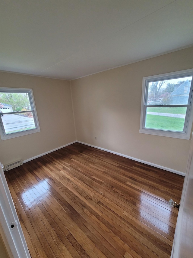 empty room featuring baseboards, plenty of natural light, and hardwood / wood-style flooring