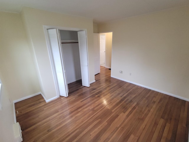 unfurnished bedroom featuring a closet, baseboards, and wood finished floors