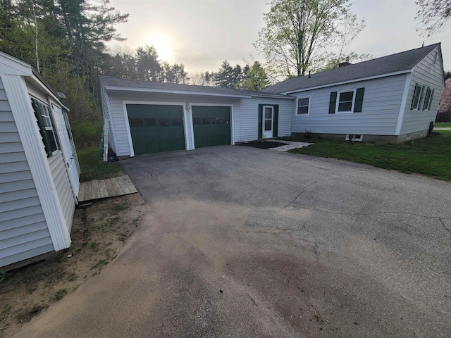 ranch-style house featuring an attached garage and aphalt driveway