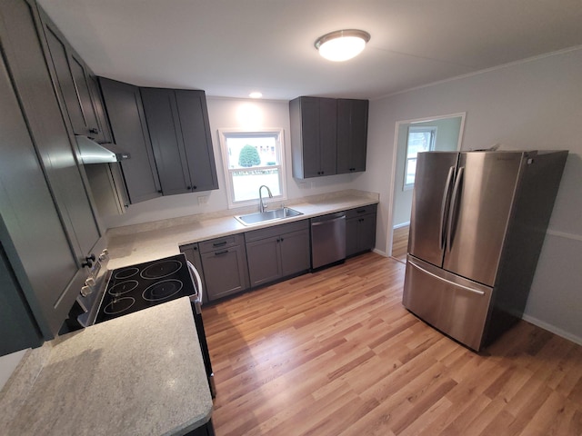 kitchen featuring appliances with stainless steel finishes, a sink, baseboards, light countertops, and light wood-style floors