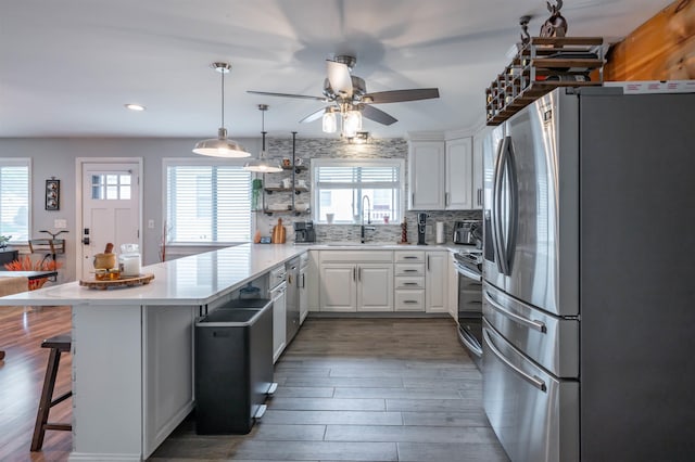 kitchen with a peninsula, light countertops, white cabinetry, tasteful backsplash, and appliances with stainless steel finishes