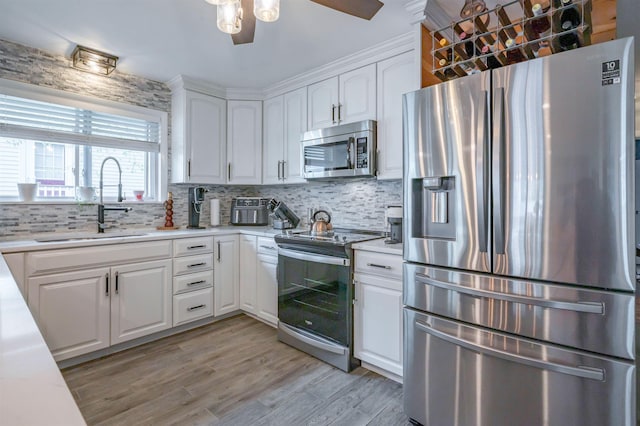 kitchen with a sink, white cabinetry, backsplash, and stainless steel appliances