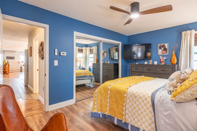bedroom featuring ceiling fan, wood finished floors, baseboards, a baseboard radiator, and a closet