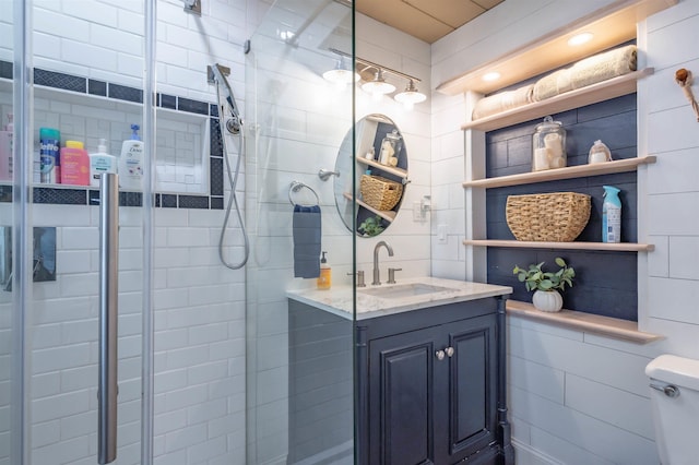full bath featuring vanity, a stall shower, toilet, and tile walls