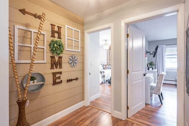 corridor featuring baseboards, wood finished floors, and baseboard heating