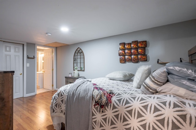 bedroom with ensuite bathroom and light wood finished floors