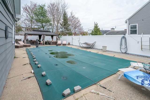 view of swimming pool featuring a fenced backyard, an outdoor hangout area, a fenced in pool, a patio area, and a gazebo
