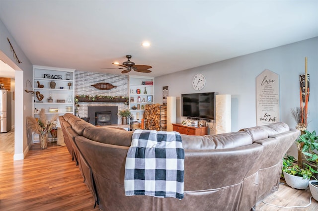 living area featuring ceiling fan, built in shelves, baseboards, recessed lighting, and light wood-style flooring