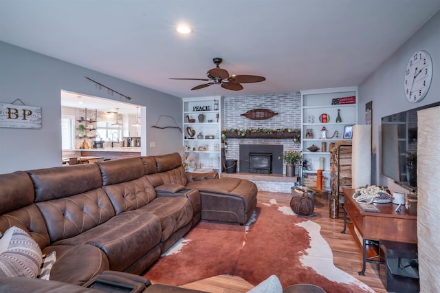 living room featuring a fireplace, a ceiling fan, and wood finished floors