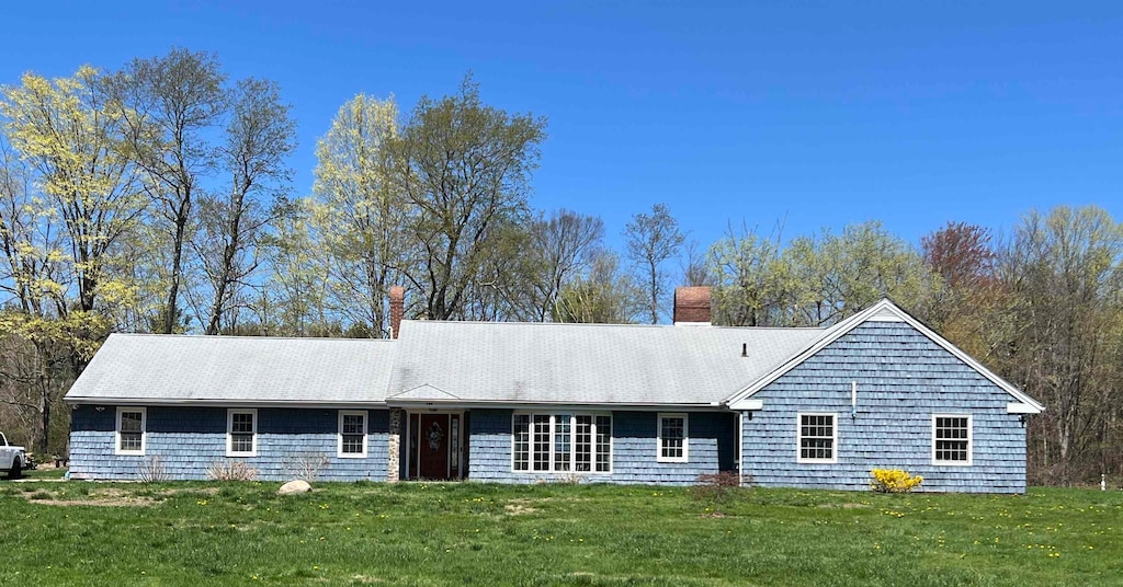 ranch-style house featuring a chimney and a front lawn