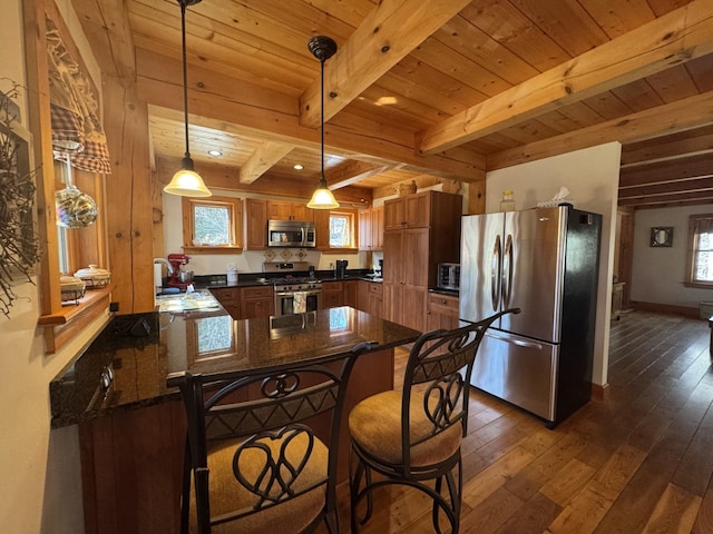 kitchen with brown cabinets, a peninsula, appliances with stainless steel finishes, and dark wood-type flooring