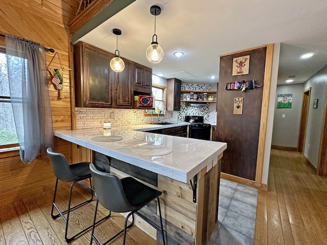 kitchen featuring a kitchen breakfast bar, backsplash, open shelves, light countertops, and a peninsula