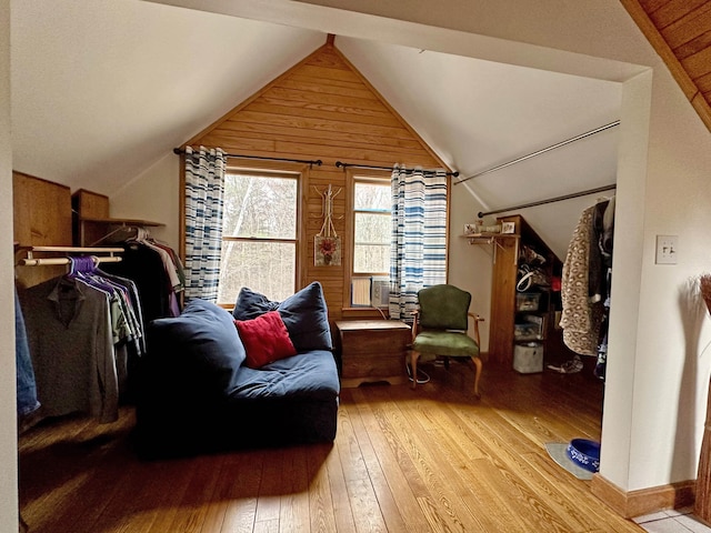 bedroom with wooden walls, wood-type flooring, and lofted ceiling
