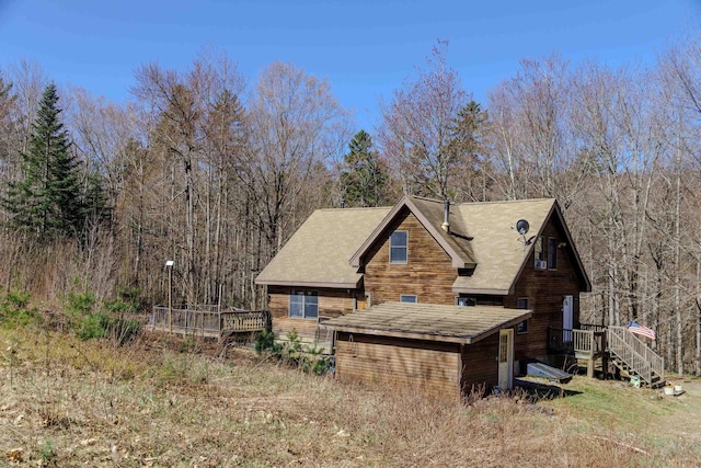 view of home's exterior with a wooded view and a deck