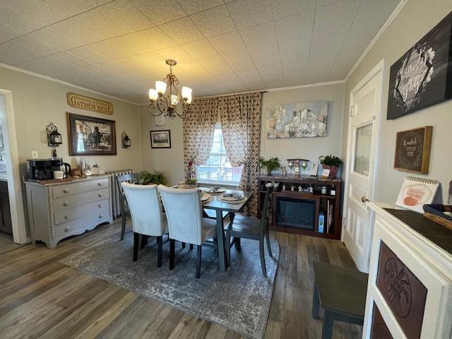 dining room with ornamental molding, wood finished floors, and a chandelier