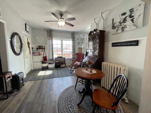 living area with a ceiling fan, baseboards, wood finished floors, and radiator
