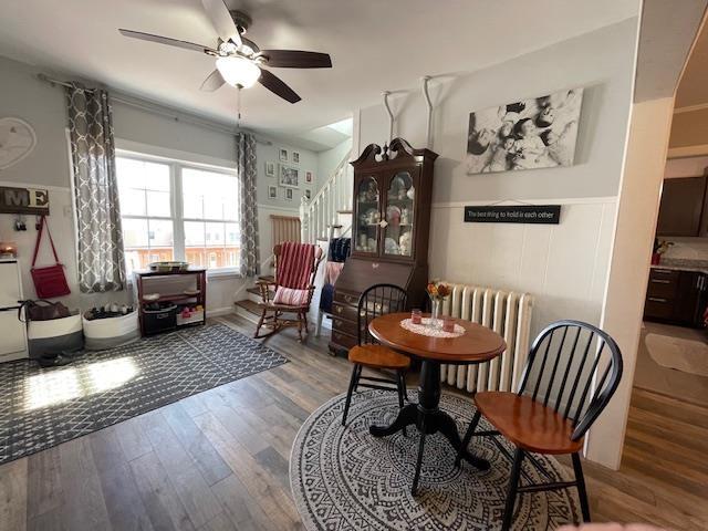 dining area featuring radiator, a ceiling fan, stairs, and wood finished floors