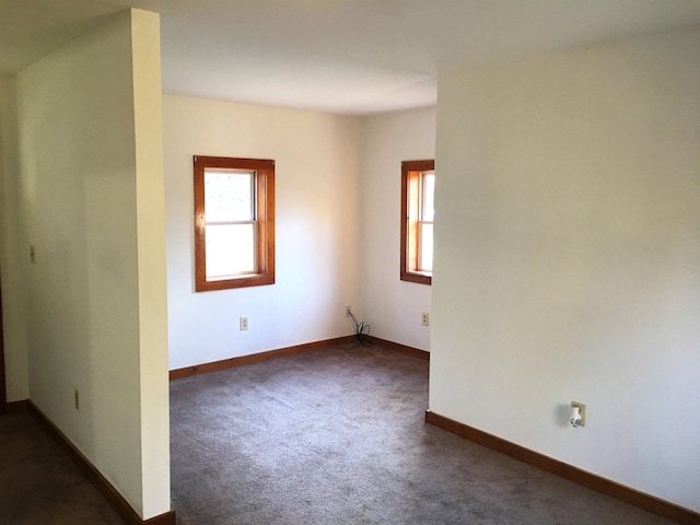 empty room with baseboards and dark carpet