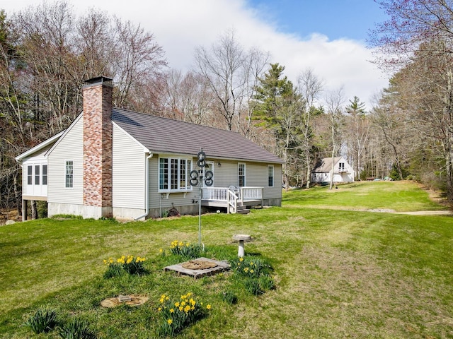 rear view of house with a lawn, a chimney, and a deck