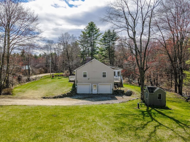 view of side of home featuring a garage, a storage unit, a lawn, and driveway