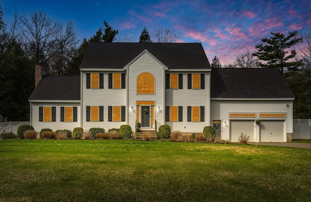 colonial home with an attached garage, a front lawn, aphalt driveway, and a chimney