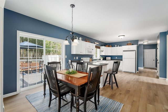 dining space with an inviting chandelier, light wood finished floors, and baseboards