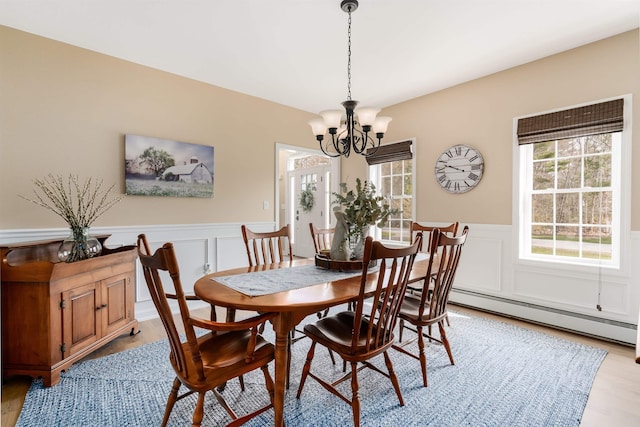 dining area with a decorative wall, light wood finished floors, and a notable chandelier