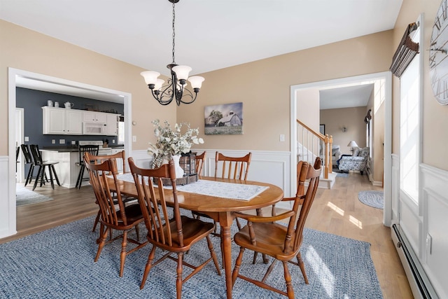 dining area with an inviting chandelier, light wood-style flooring, and baseboard heating