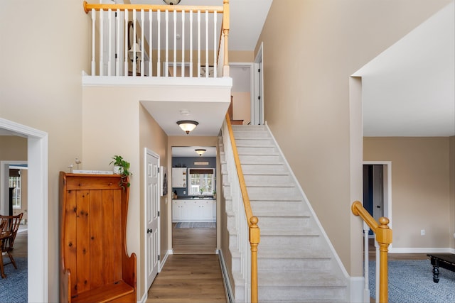 staircase with baseboards, a baseboard radiator, and wood finished floors