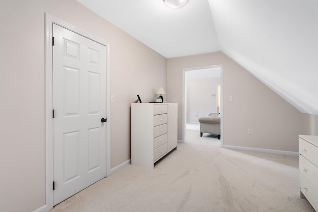 bedroom with light colored carpet, baseboards, and vaulted ceiling