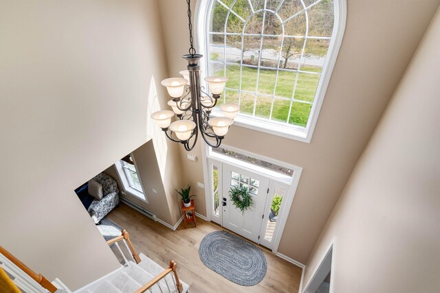 foyer entrance with baseboards, a high ceiling, an inviting chandelier, and wood finished floors